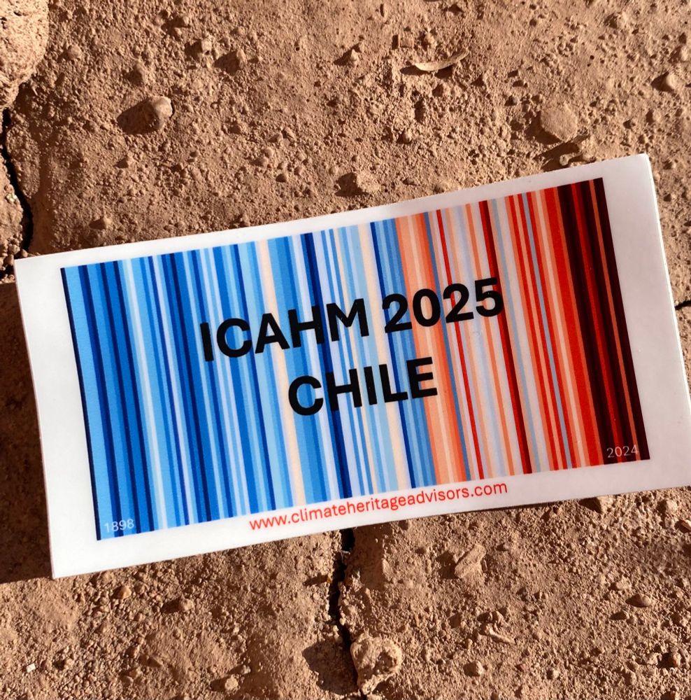A #ShowYourStripes sticker showing the last 125 years climate for Chile in vertical stripes from left to right, mainly blue on the left and getting more red to the right. The sticker is laid on some adobe in the sun. Across the stripes it says in black: ICAHM 2025 Chile. ICAHM is an acronym for the International Committe on Archaeological Heritage Management. At the bottom of the sticker is a web address: www.climateheritageadvisors.com