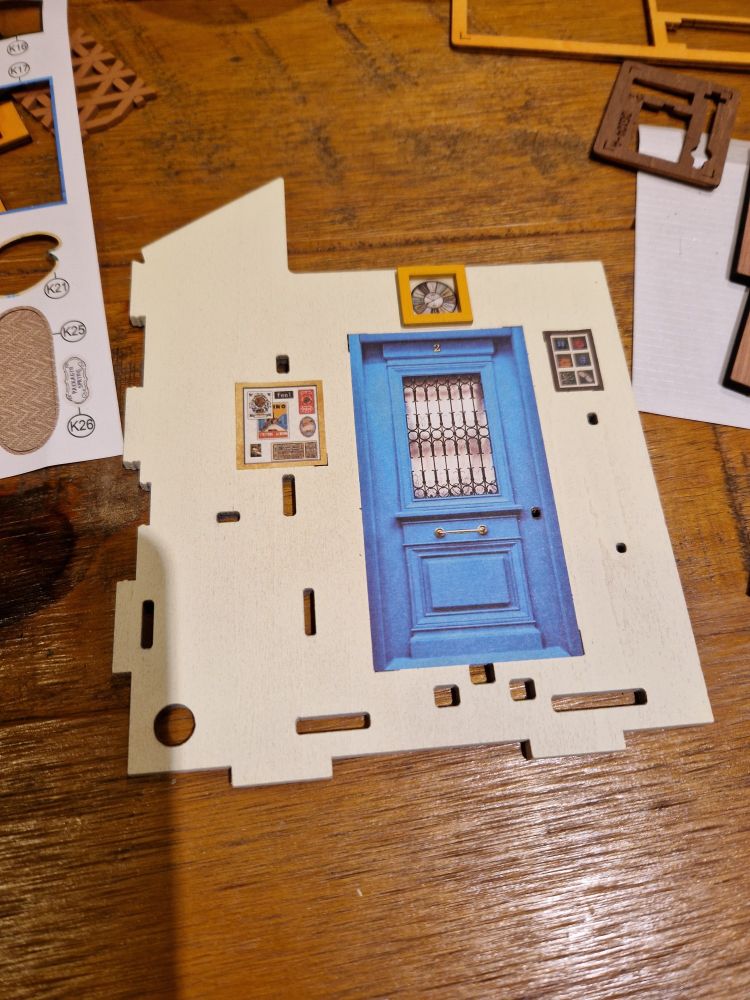 Wooden wall piece with door and pictures stuck on 