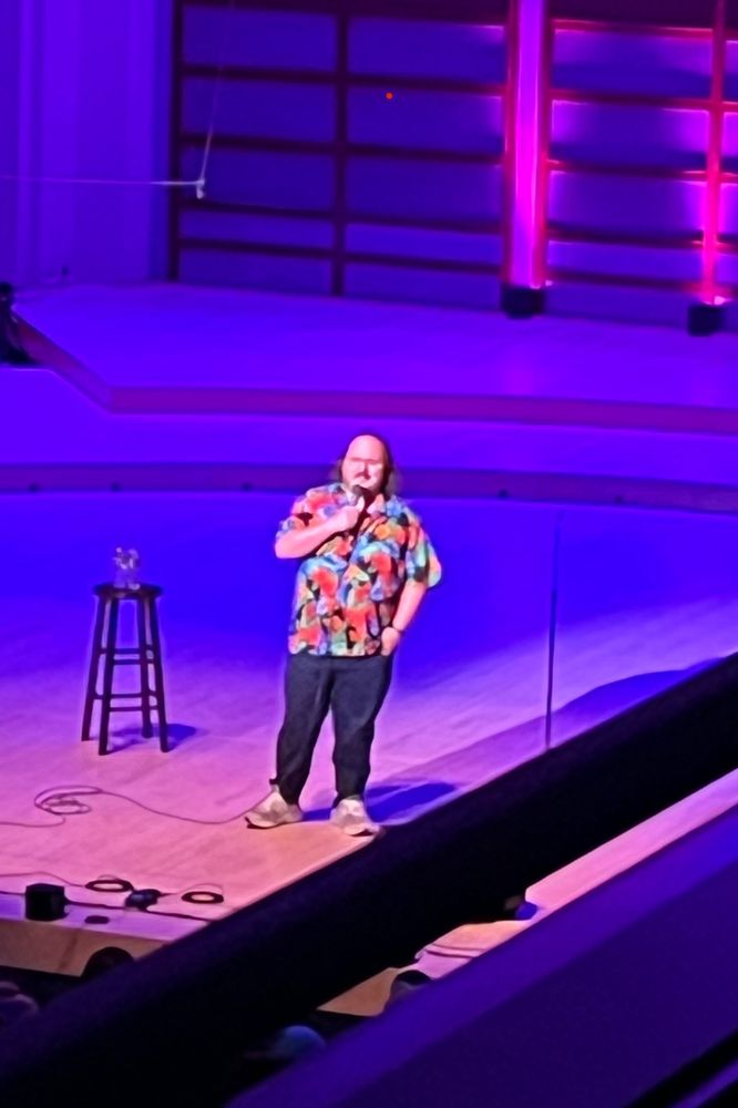 Stavros Halkias standing on stage delivering some hilarious jokes and stories.