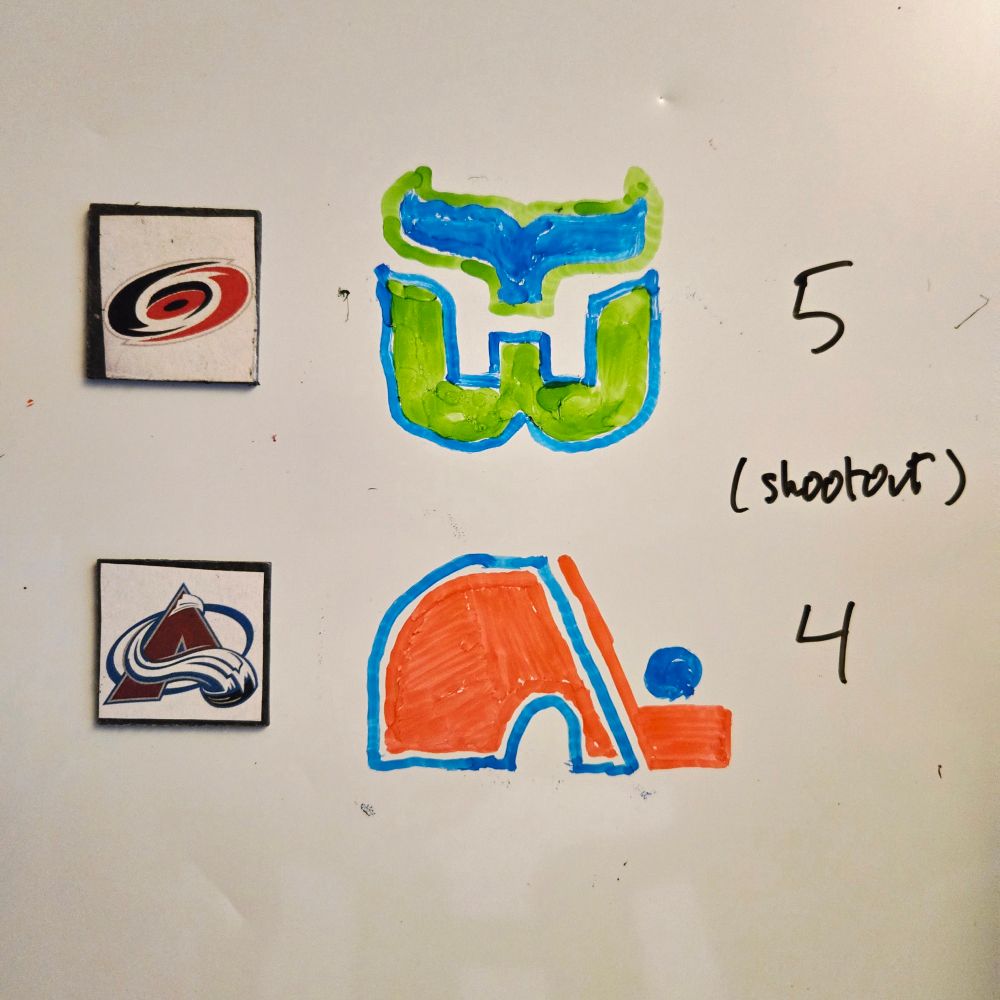 A whiteboard displays two small magnets with Carolina Hurricanes and Colorado Avalanche logos. Beside those are marker-sketched Hartford Whalers and Quebec Nordiques logos respectively, and the score 5-4 (shootout).