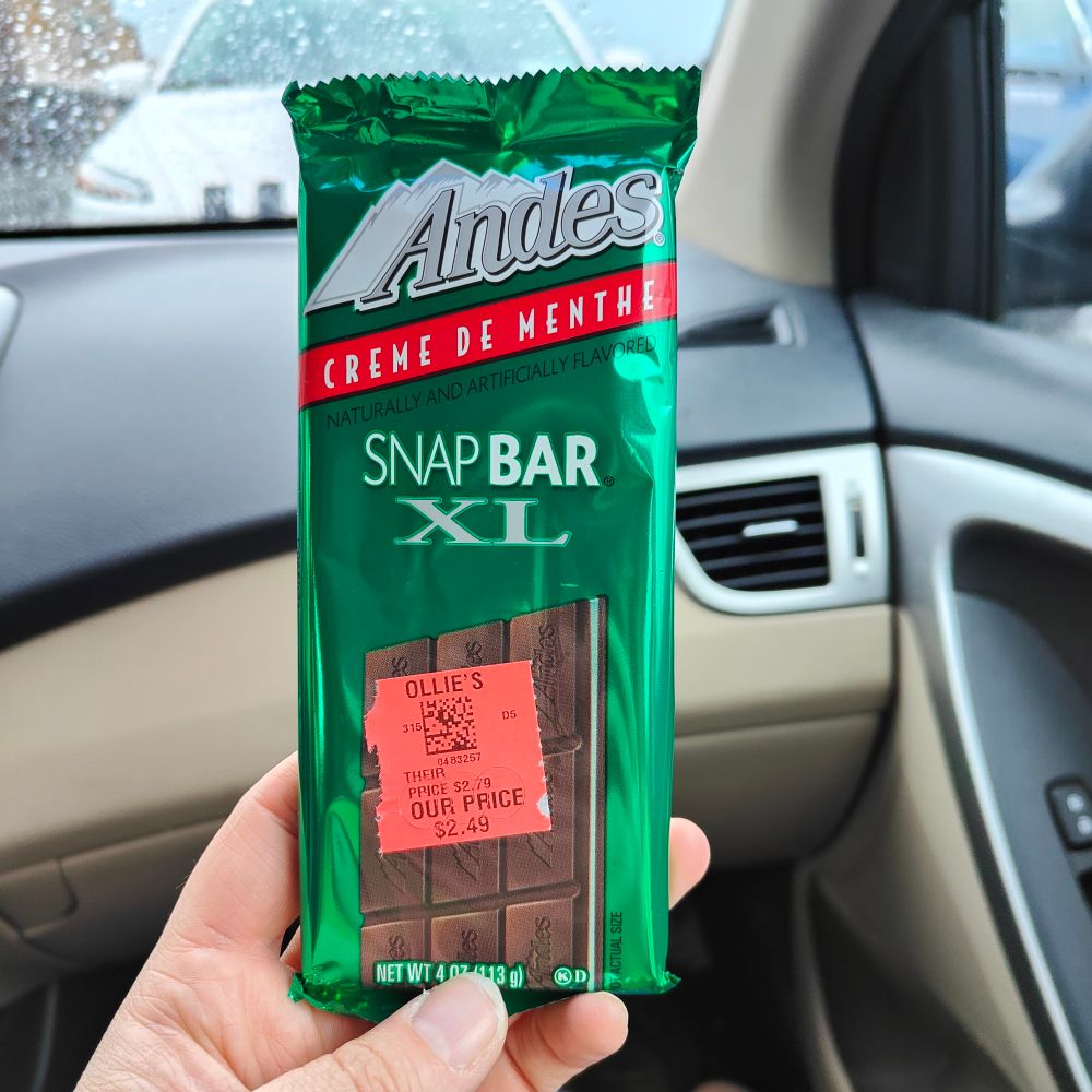 A close up of my left hand holding up an Andes Creme de Menthe candy bar. The wrapper is green and has the Andes logo at the top.