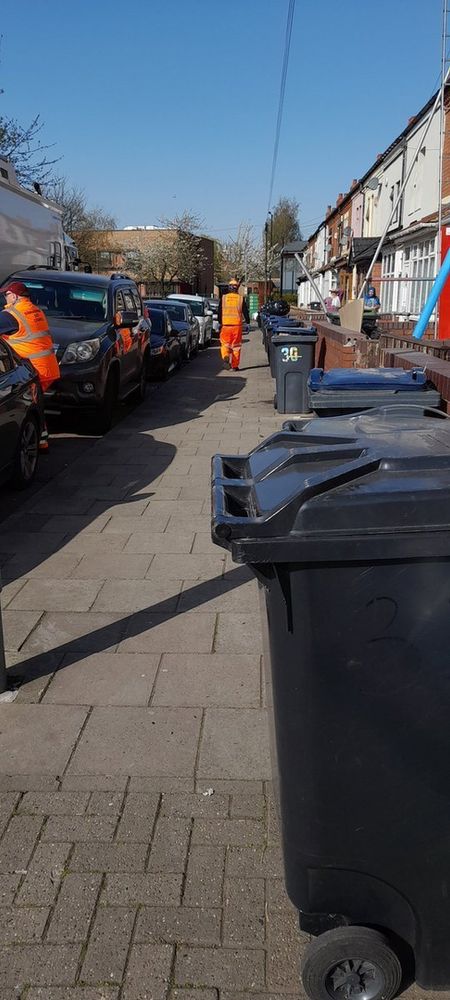 Photo of lined up wheelie bins and bin crew walking up the street