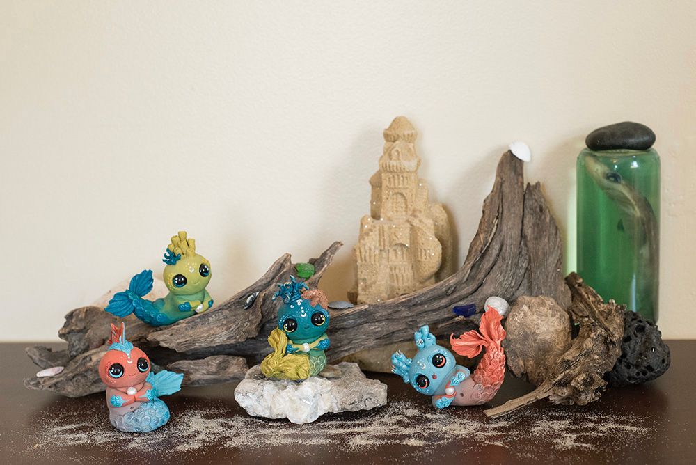 2016: Four handmade polymer clay mermaid figurines sculpted in Mishes old art style of oversized head with huge, sad eyes, and a plump bellies. Sitting on a shelf with sand, sand castle, driftwood, & shark in a jar.