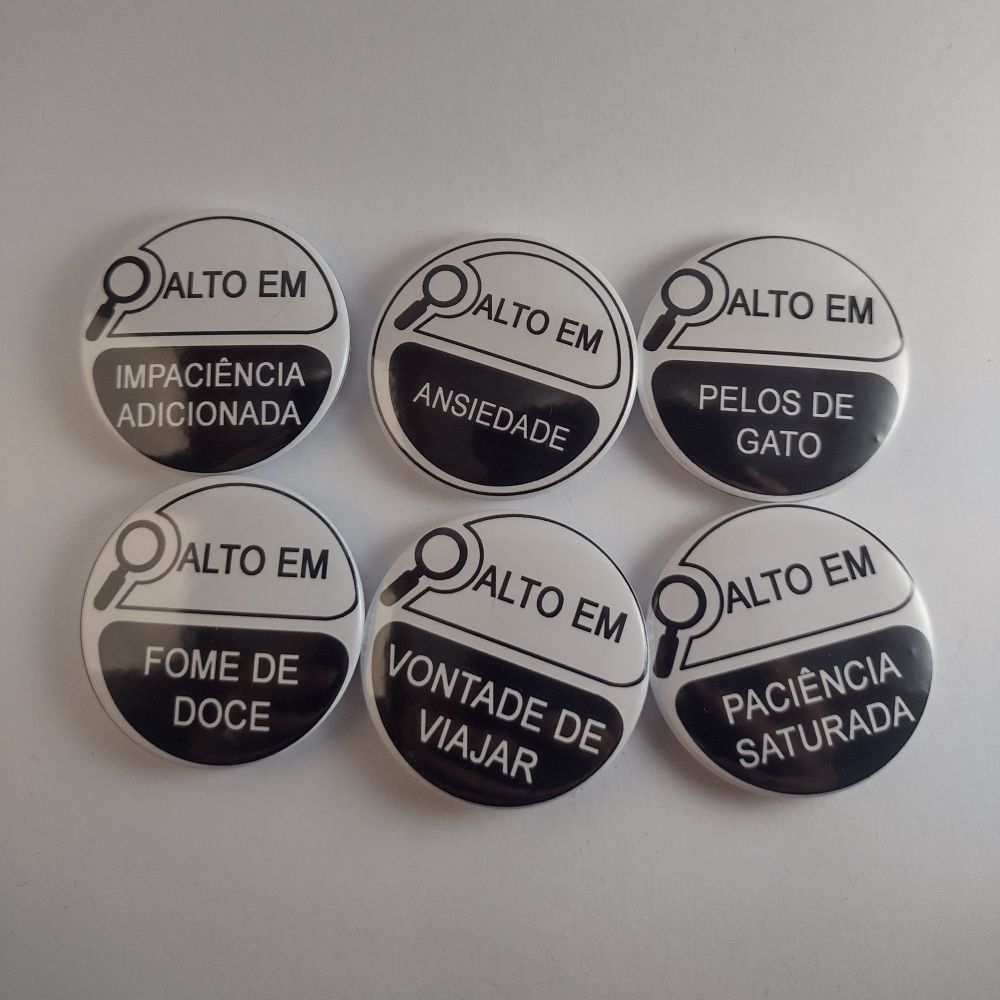 Bottons redondos alinhados em duas fileiras com três, lado a lado.
Eles imitam o design dos avisos de alerta de conteúdo de alimentos, em preto e branco com uma lupa e a inscrição "alto em" na parte de cima e a coisa na qual é alto escrito em baixo. Nos bottons da fileira de cima lê -se
Alto em: impaciência adicionada, ansiedade e pelos de gato
Na fileira de baixo: fome de doce, vontade de viajar e paciência saturada 