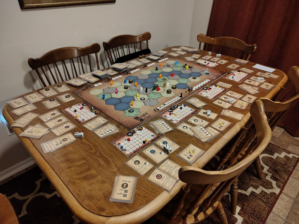 A table covered with the game board, pieces, and cards of Knights Errant.
