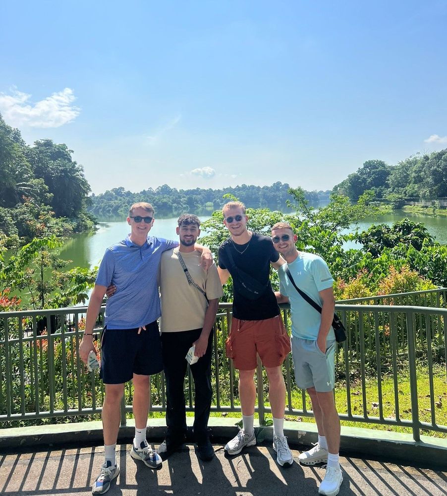 Adam Diab, Callum Samuel, Ewan McCall and Josh Duncan, in Singapore for the SUSS Global Impact StartUp Challenge 2025 in July. They have a lake surrounded by trees behind them.