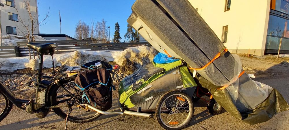 An adult size single bed + mattress strapped together on a sackbarrow, which is then tightly strapped at a horizontal angle to the back of the bike trailer.