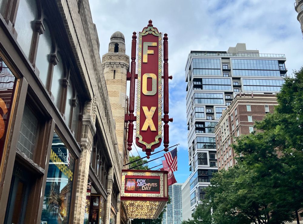 The fox theatre’s red sign with gold letters that spell FOX. Beneath it is a screen that says FOX ARCHIVES DAY
