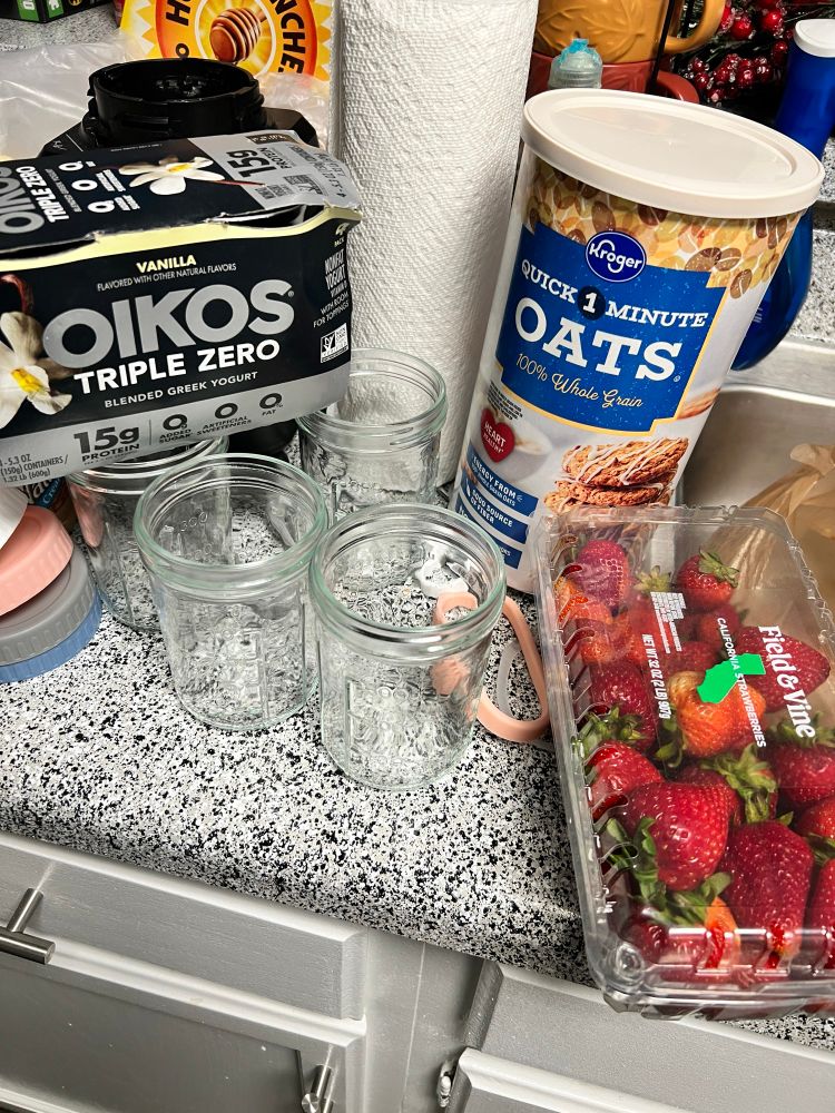 oikos triple zero yogurt, strawberries, whole grain oats on a kitchen counter with empty jars