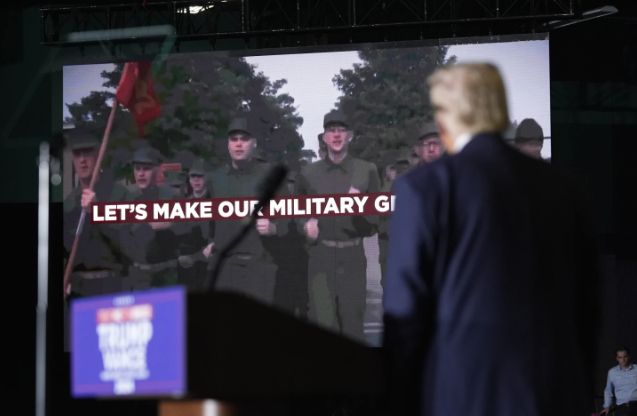 Drumpf in the foreground with a scene from the Warner Bros. movie Full Metal Jacket in the background with the line 'Let's Make Our Military Great Again' plastered over it. 