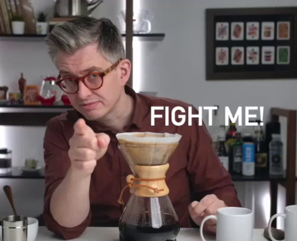 a man is pointing at a coffee maker with the words fight me behind him