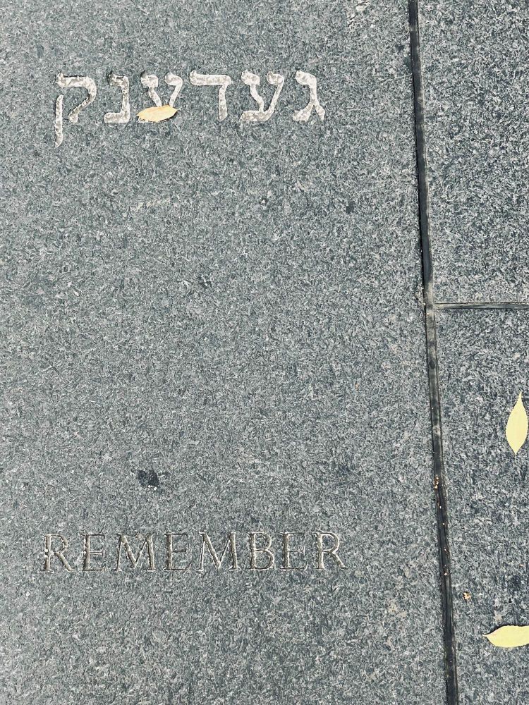 Zwei Inschriften auf dem Boden, in hebräischer und lateinischer Schrift: Remember