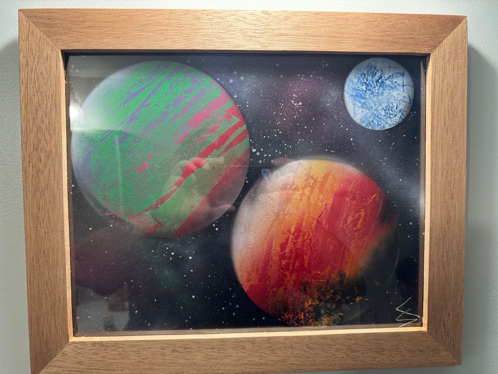 A framed picture of spray paint planet art