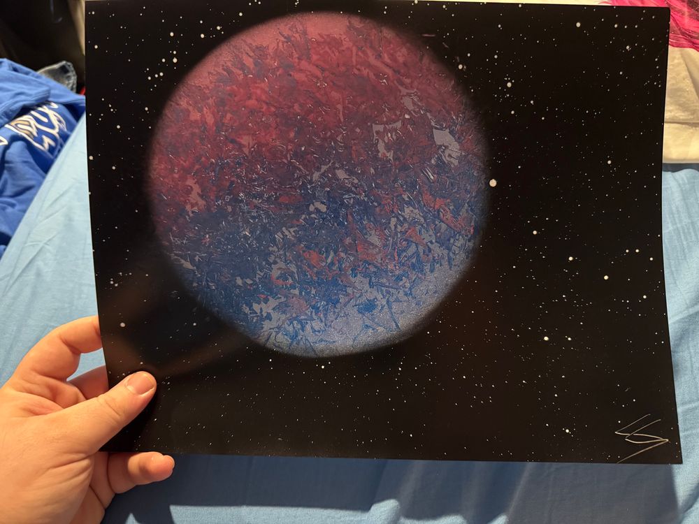 A spray paint art piece of a purple and blue planet on a starry background