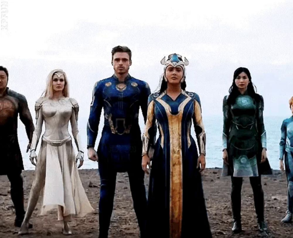 a group of people dressed in superhero costumes are standing next to each other on a beach .