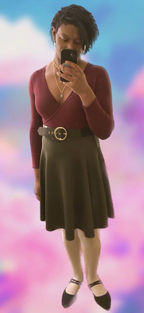 Maya in a dark red top and dark green Siri with belt, jewelry, makeup and white tights.