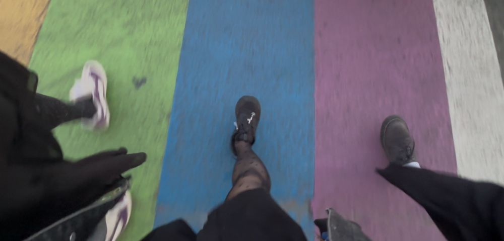 The feet of three people walking on a pride flag painted crosswalk in Seattle 