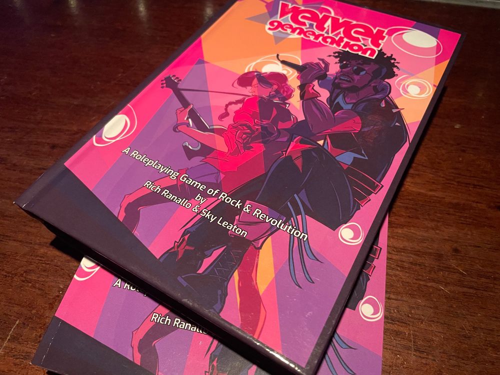 Two copies of Velvet Generation on the cover of the bar at Logan Arcade, the covers read “a roleplaying game of rock & roll revolution by Rich Ranallo & Sky Leaton”