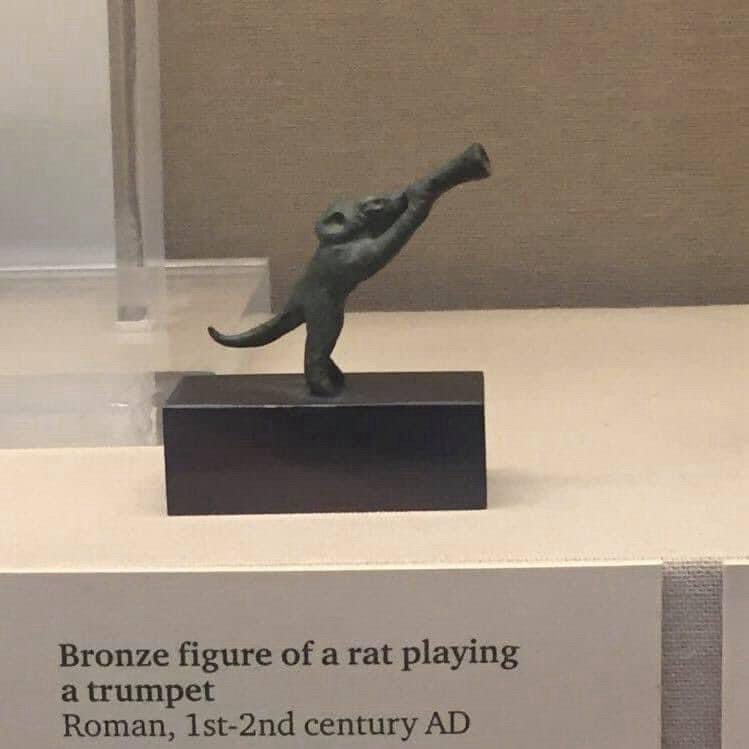 A figurine of a mouse playing a trumpet, in a museum. The card reads 

Bronze figure of a rat playing a trumpet
Roman, 1st-2nd century AD