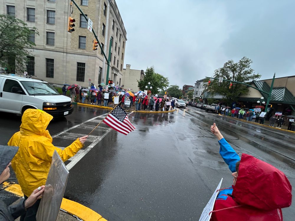 Intersection in front of a us post office filled with protestors in the rain
