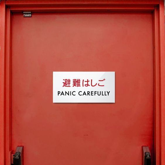 Eine rote Flucht Tür mit chin. Schriftzeichen, darunter die Übersetzung "PANIC CAREFULLY"