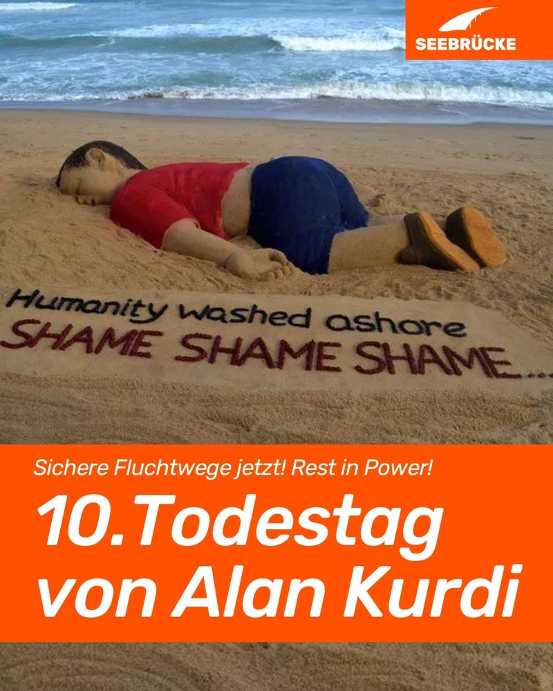 Foto einer Sandskulptur des ertunkenen Alan Kurdi in rotem T-Shirt und blauer Shorts. Darunter steht auf dem Sand "Humanity washed ashore. Shame shame shame". In einem orangen Kasten steht "Sichere Fluchtwege jetzt! Rest in Power! 10. Todestag von Alan Kurdi". In der rechten oberen Ecke ist das Seebrücke-Logo in weiß auf orange.