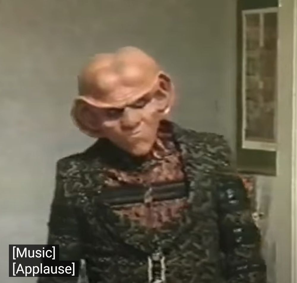 a vaguely menacing quark saunters onto the set with subtitles saying [music][applause]
