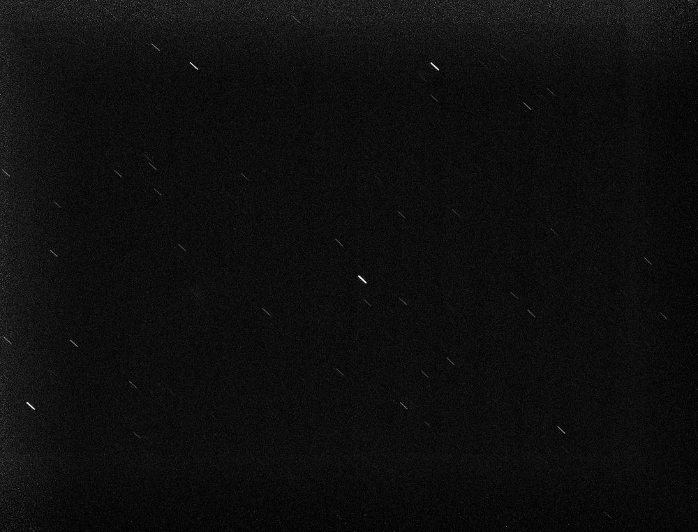 image of the night sky showing a starfield with several dark and bright stars that are quite elongated due to the long exposure time.