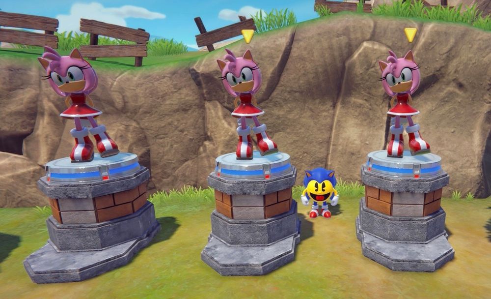 Three Amy Rose statues standing atop three pedestals. Pac-Man, dressed as Sonic, stands between the two on the right