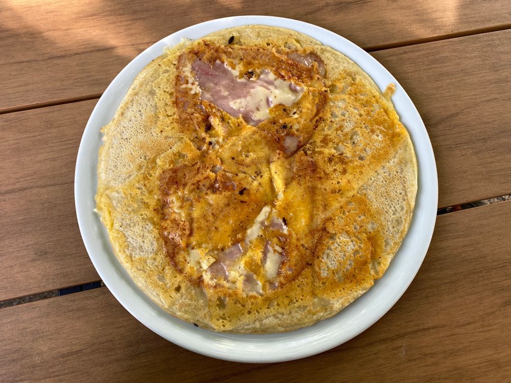 a beautiful round pancake with two slices of ham and crunchy cheese on it