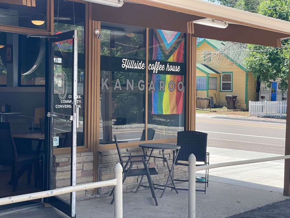 A picture of a coffee shop called Kangaroo coffee with a pride flag in the window. I stopped here to get kangaroo merch because of course I did