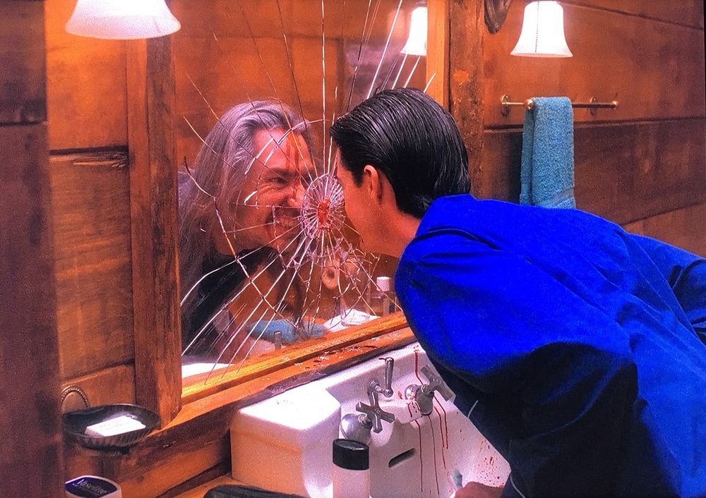 Final scene from season 2(?) of Twin Peaks. A man has bashed his head into a mirror. The image in the mirror is of a completely different person, slightly deranged looking, with long, stringy grey hair. There is some blood. 
