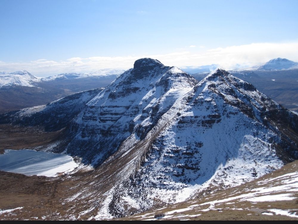 Photo of Quinag in north west Scotland with snow on the hill and blue skies.