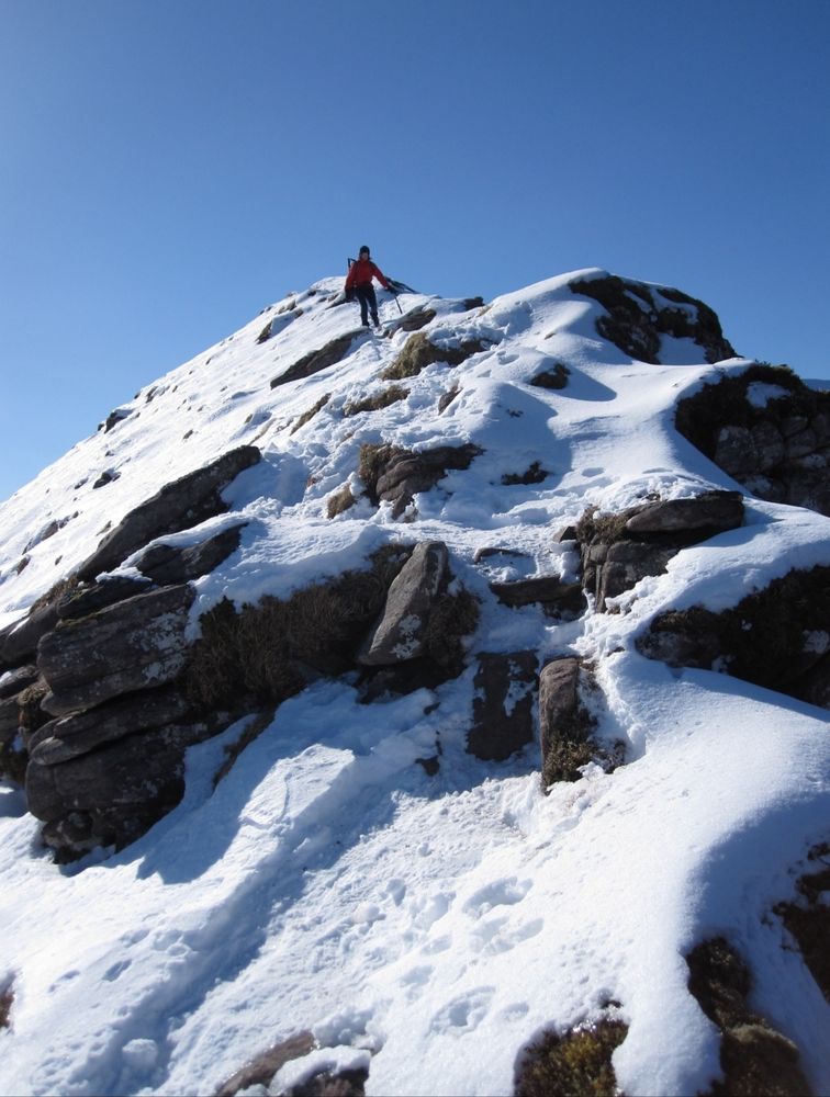 A figure descending a snowy ridge.