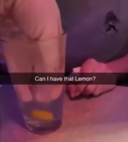 snapchat screenshot of a person reaching their hand into someone elses water cup to get the lemon at the bottom. Text says "Can I have that Lemon?"