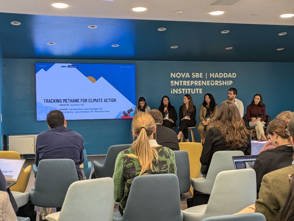 6 people in a panel discussion sitting on chairs in in front of the audience