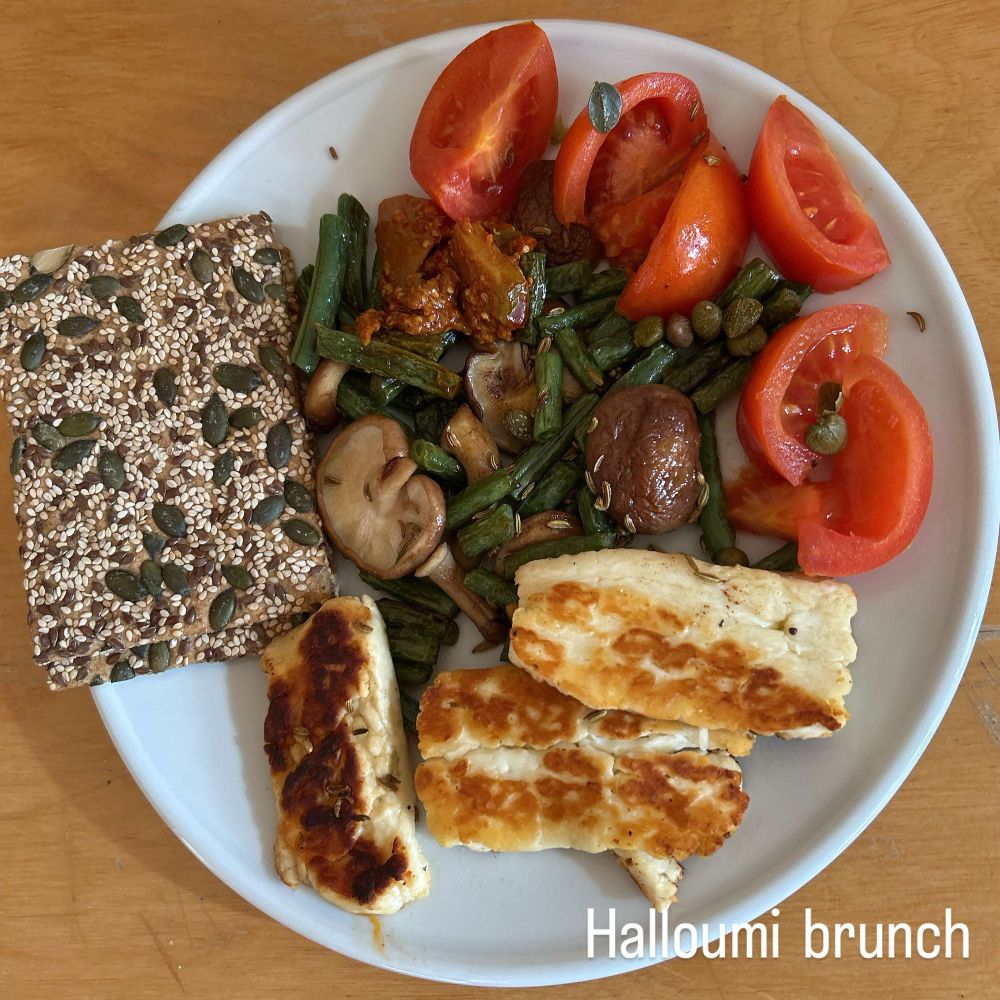 Colourful brunch of halloumi, seeded crackers, tomatoes, beans, mushrooms and dressing 