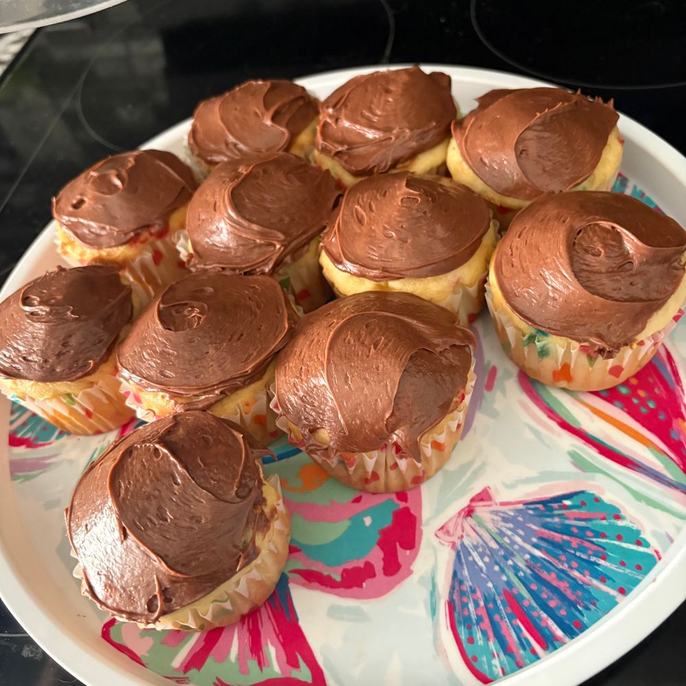 A tray of chocolate frosted funfetti cupcakes.