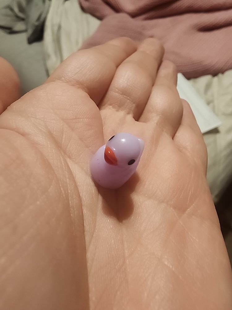 photo of very important tiny purple duck sitting in the palm of my hand. it is smaller than my thumb