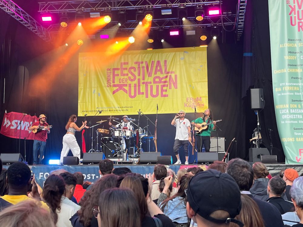 Bühne mit der Gruppe Calle Mambo. Davor ZuschauerInnen. 
