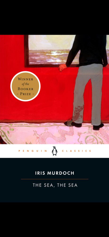 Cover of “The Sea, the Sea” by Iris Murdoch, a Penguin Classics edition where the lower quarter of the cover is plain black, with the title and author in white. Above is an illustration showing the torso and legs of man, facing away as he looks out a window (or looks at a painting of a window). The window shows the sea with sunlight reflecting on its waves. The room has a bright red wall, and the man is standing on a pinkish carpet decorated with Chinese dragons. One of the dragons has lifted from the carpet and is climbing on his leg. 