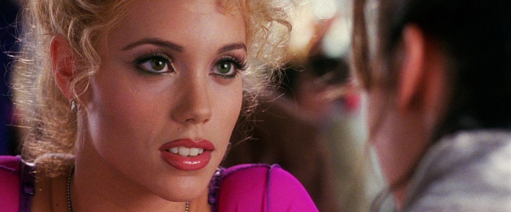 a still from SHOWGIRLS of Elizabeth Berkley in close-up as Nomi Malone