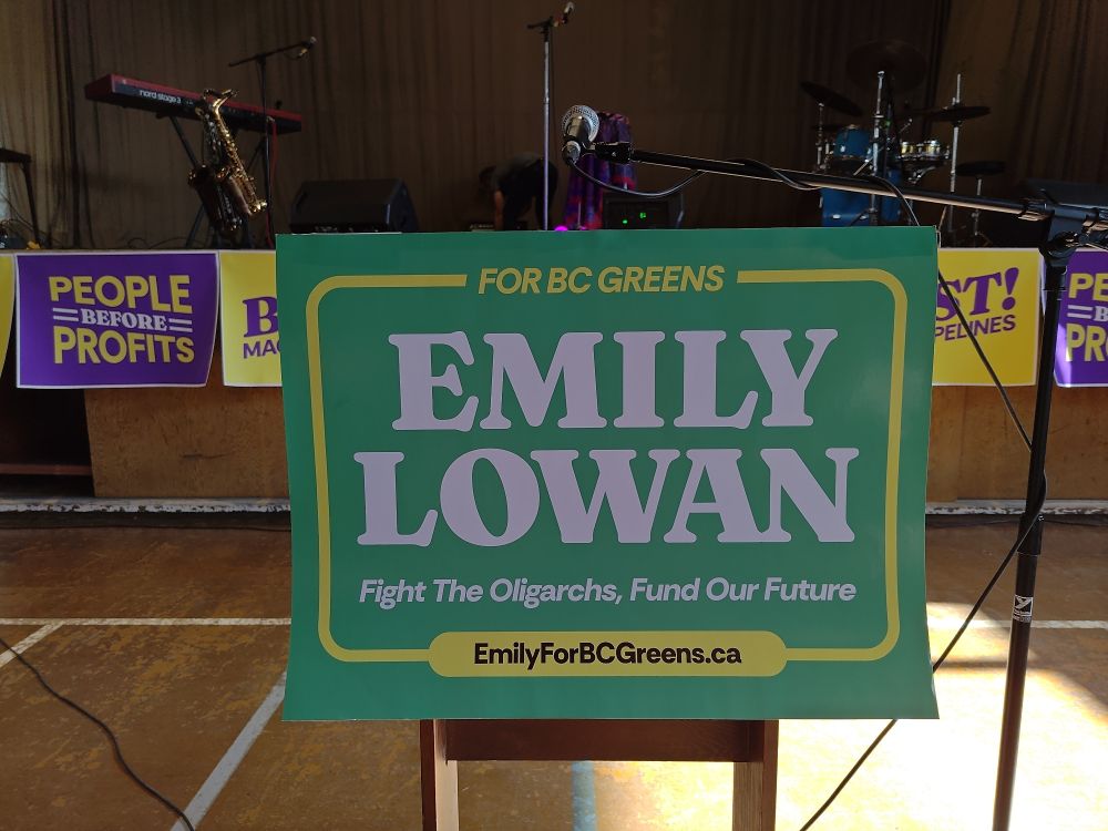Emily Lowan's slogan, as seen on a podium. "Fight The Oligarchs, Fund Our Future."