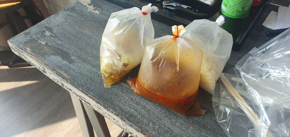 Three small plastic bags sealed with rubber bands containing fried cabbage, a red curry, and rice 