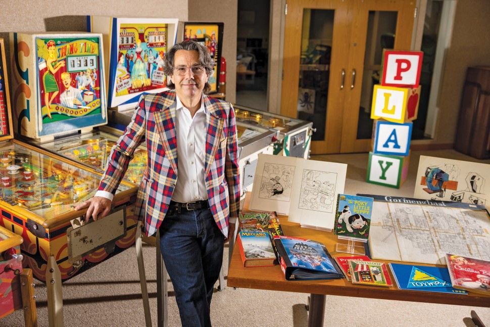 David Sleasman, librarian of the Brian Sutton-Smith Library and Archives of Play, in front of pinball machines and next to several items from the library's collections.
