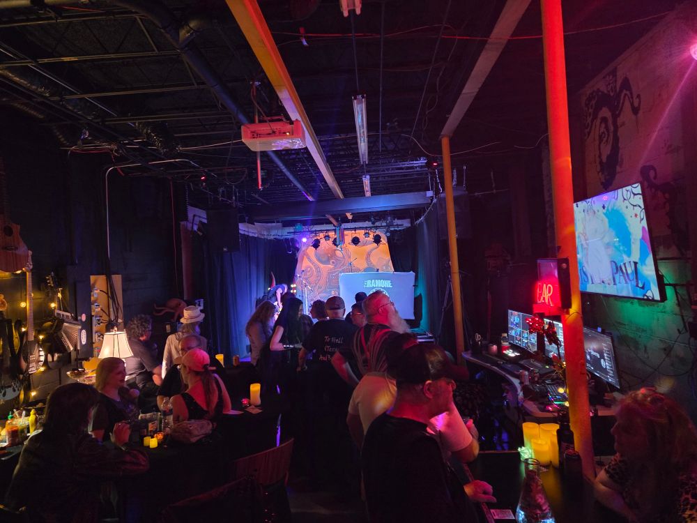 Rocky The Ramone on stage at Nano Tako Studio.  Rocky is a One Man Tribute band to the Ramones.  Rocky is on left stage with a video screen right stage.  On the video screen is Rockys logo.
