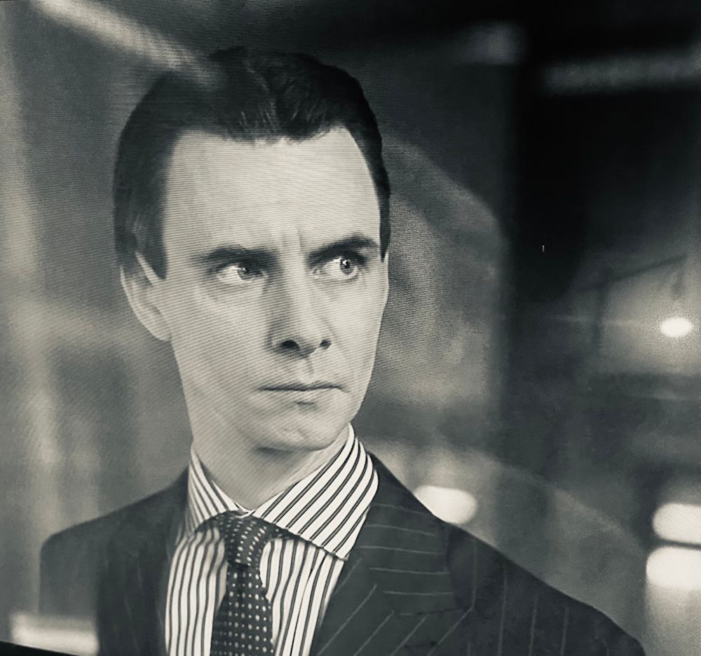 Dark haired man in pin stripe suit jacket.