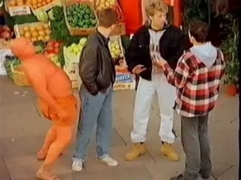 An orange man surprises three young men in the street with his uncouth and aggressive behaviour 