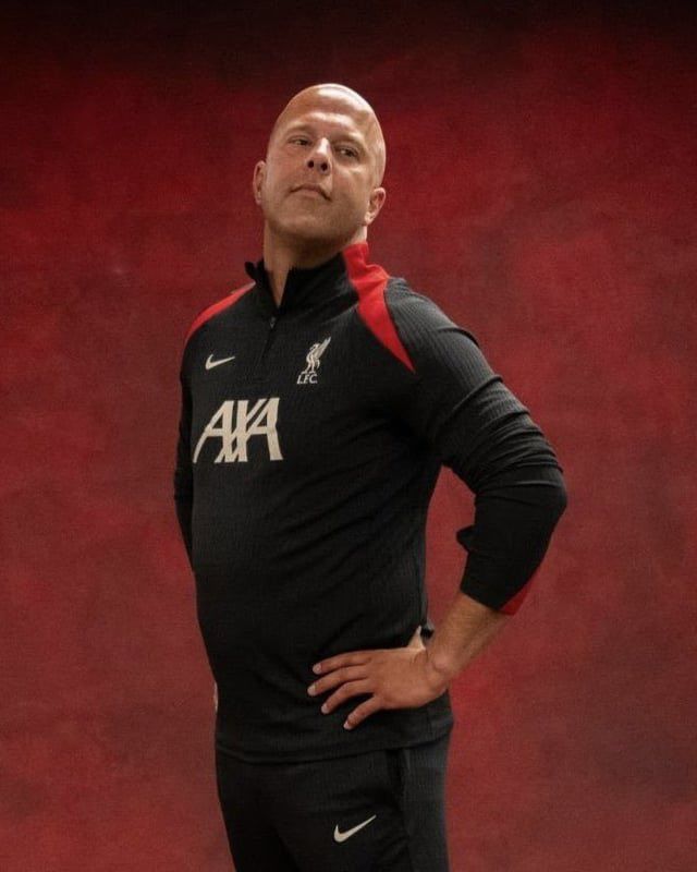 Proud Liverpool manager Arne Slot chest puffed out with hands on hips.