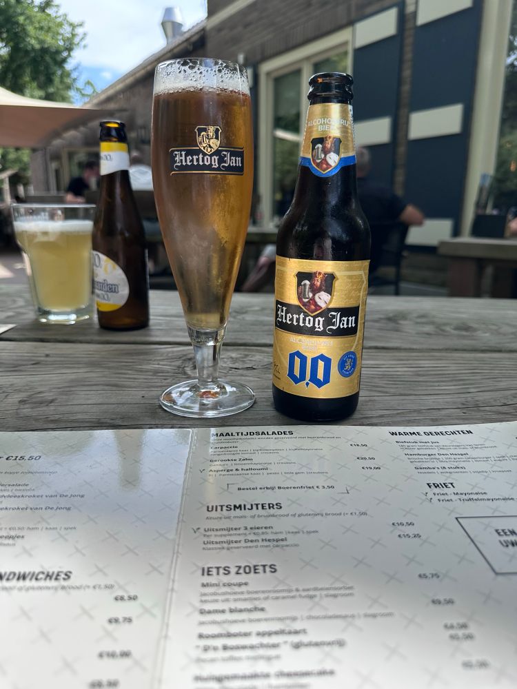 Een bierfles op een houten tafel buiten in een café